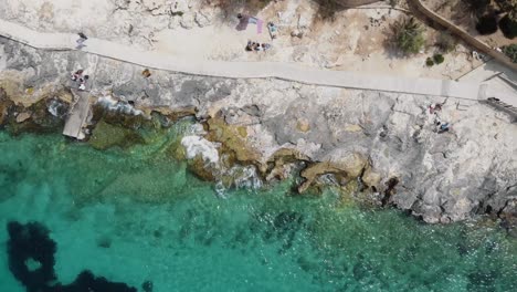 rocky sea shore eroded by the mediterranean turquoise sea in sliema, malta - rocket aerial shot