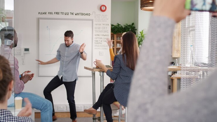 Crazy happy businessman dancing doing victory dance in team meeting celebrating success achievement