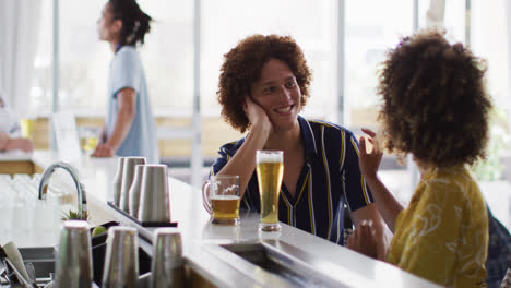 diverse group of happy friends drinking beers and talking at a bar