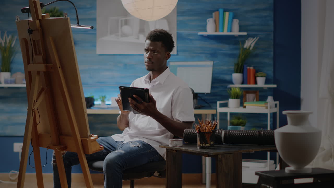 Black man artist with digital tablet in workshop studio