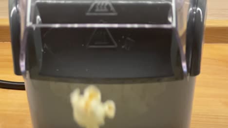 corn popping and flying from machine to the bowl. popcorn making machine in slow motion. hot air popcorn machine. converting corn into popcorn with dry hot air. corn popping in a hot air popper