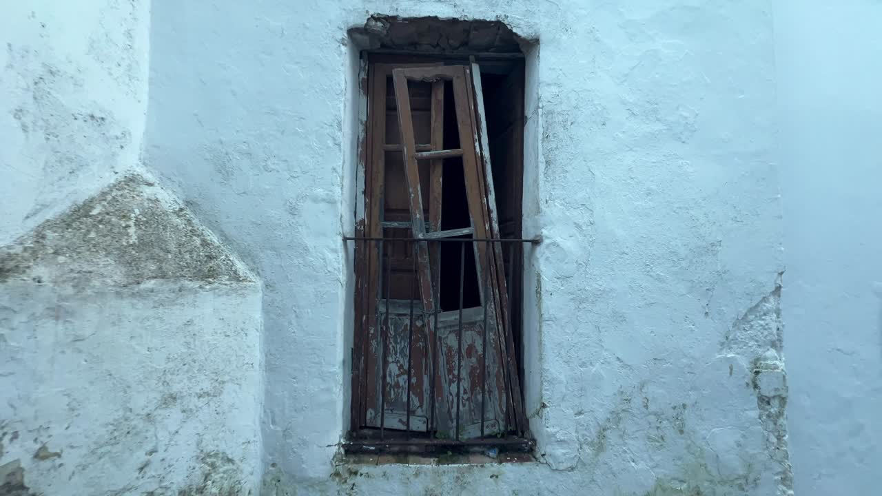 Alejamiento de una vieja ventana de madera rota en un edificio rural blanco. Luz diurna.