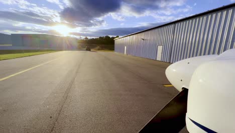 sunset push in beyond prop of piper cherokee 180 on tarmac outside hangar