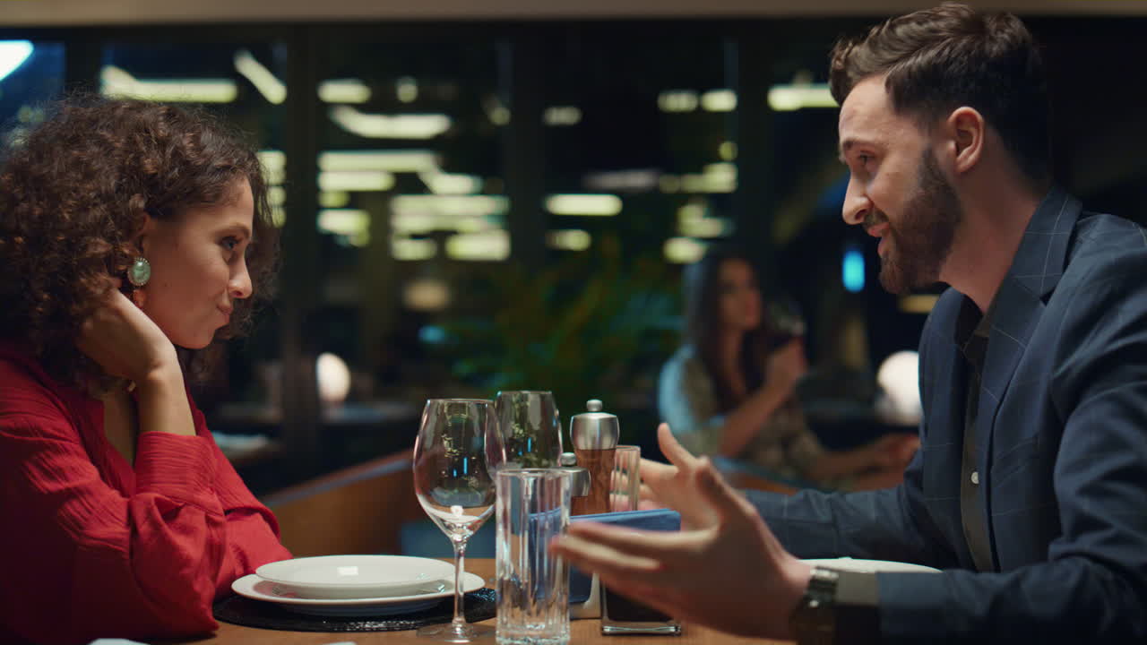 Smiling lovers talking together in night restaurant. Couple enjoy dating in bar.