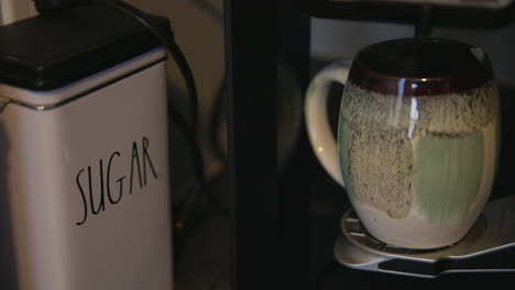 steam emerges froma chipped decorative coffee mug as coffee is dripped from a home coffee maker