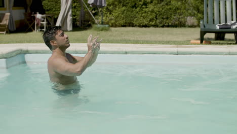 attractive male teenagers playing volleyball in swimming pool