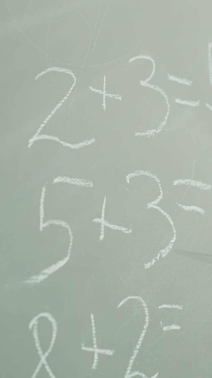 el tutor muestra una tarea de matemáticas sin resolver escrita en la pizarra con un puntero en el primer plano del aula. problemas matemáticos adicionales para la escuela primaria en la pizara