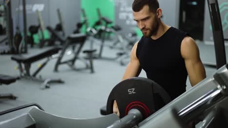 Man-Puts-Additional-Weights-on-a-Barbell.-Muscular-Fit-Guy-Performs-Leg-Exercises