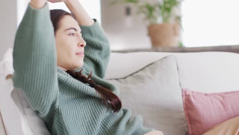 happy caucasian woman sitting on couch and stretching in living room