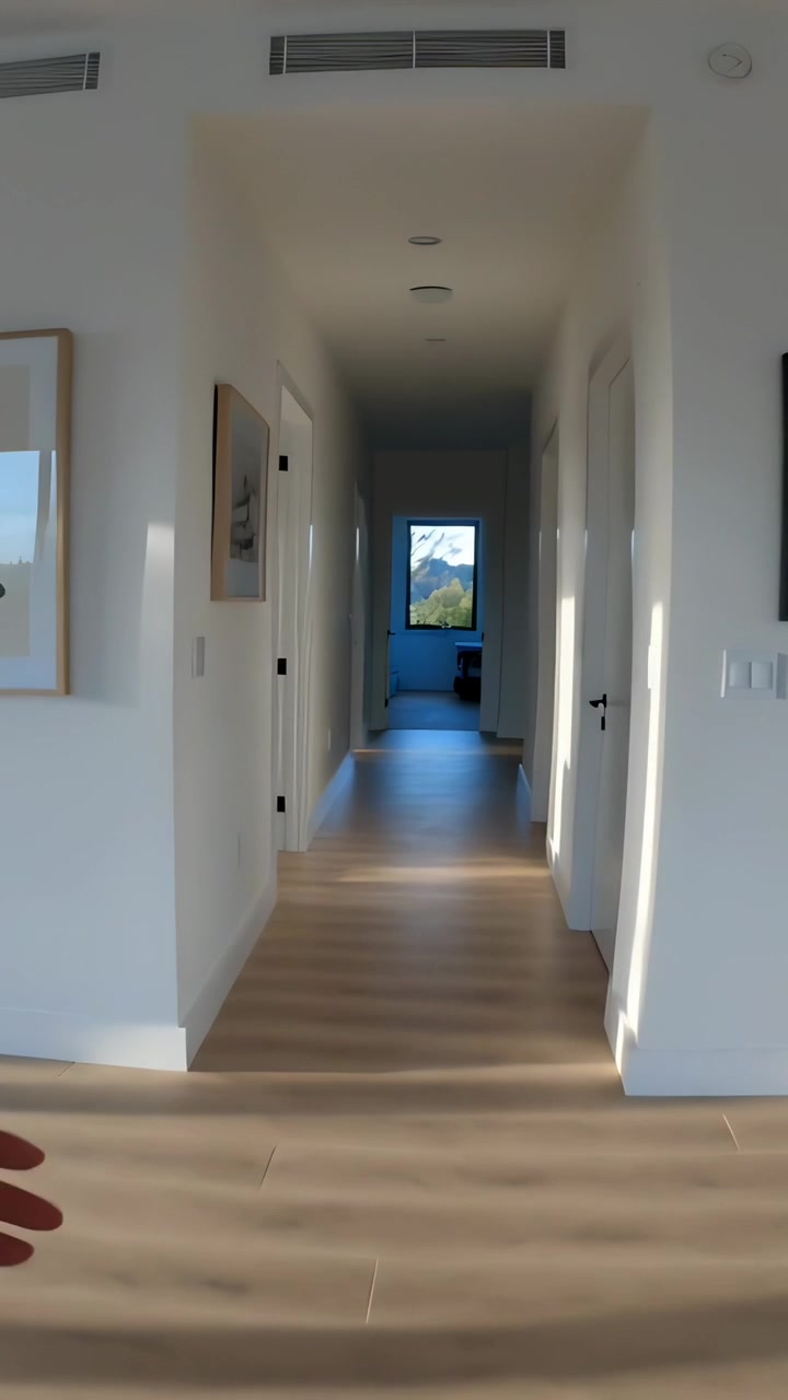 Video verticale: Telecamera che avanza in un corridoio verso una finestra in casa, mostrando un pavimento in parquet.
