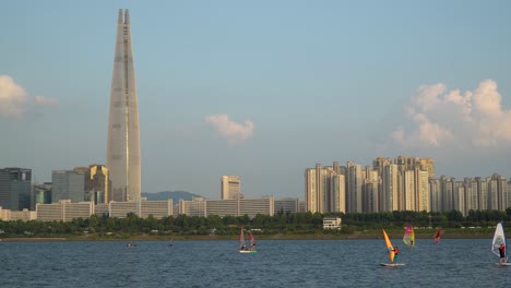 windsurfers in the han river, lotter world tower on the background at sunset, seoul, south korea