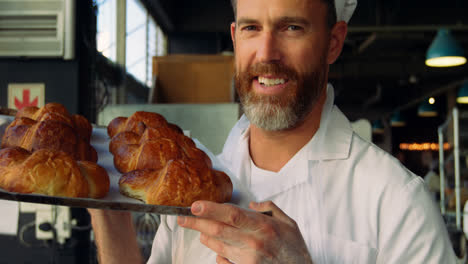 male chef holding tray of croissants in bakery shop 4k