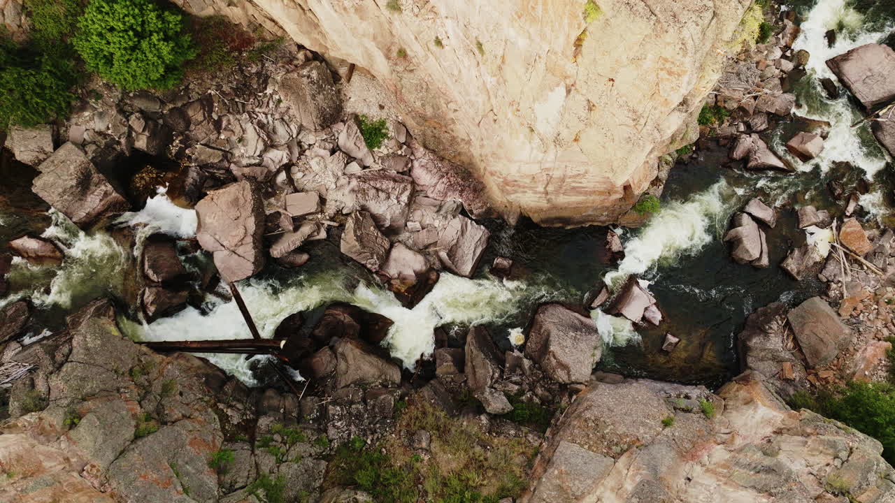 Drone shot looking straight down on river rapids in rocky canyon in Wyoming