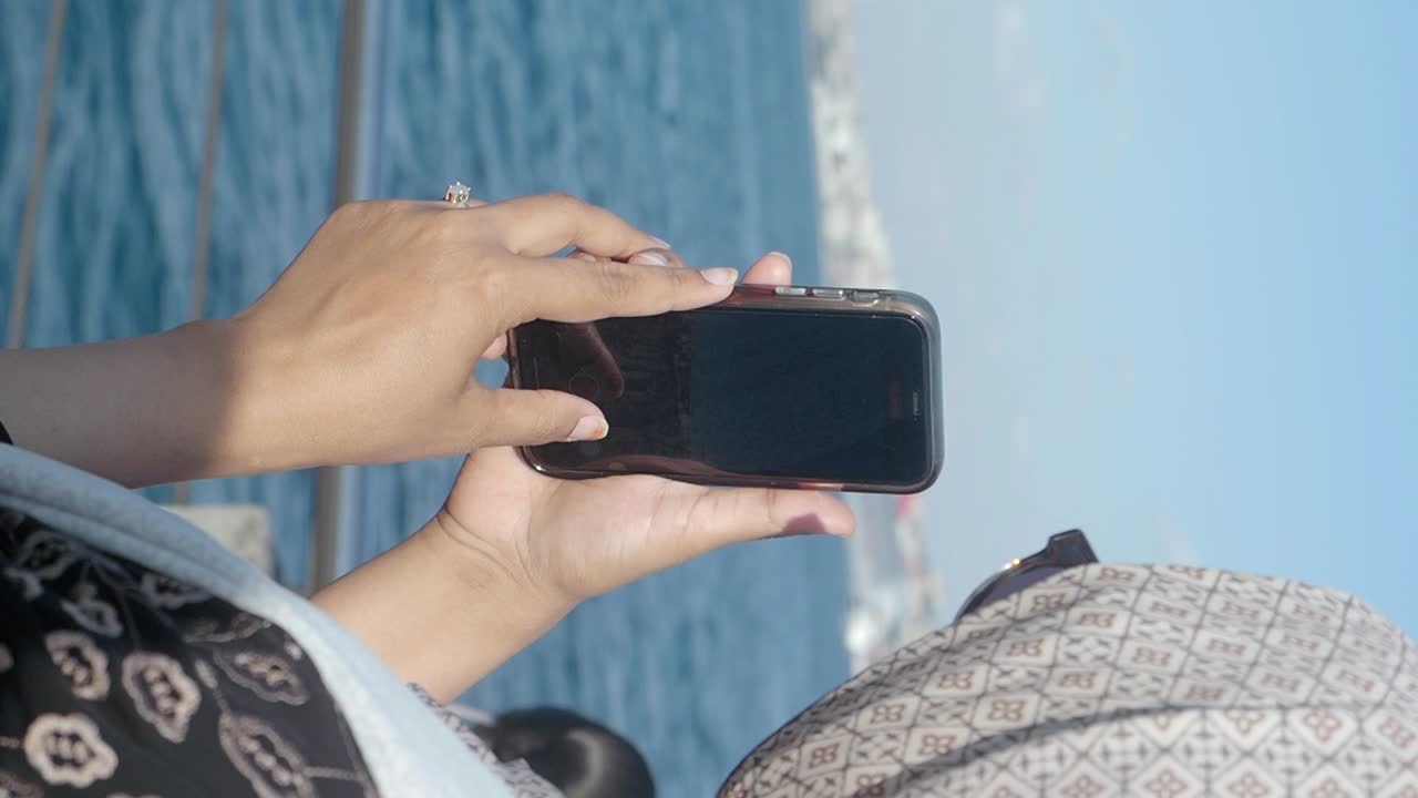 Person holding a phone over the ocean