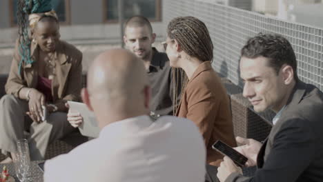 plano medio de gente de negocios sentada a la mesa en un café al aire libre