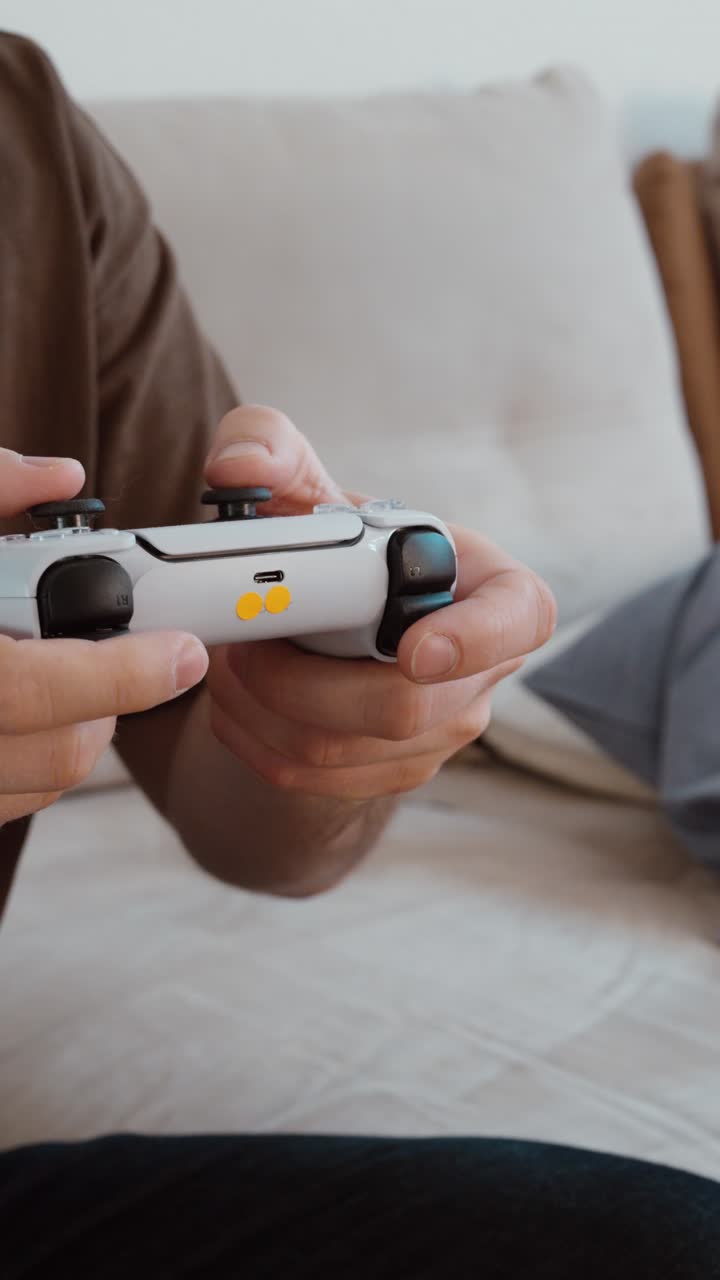 Close-up of hands holding a game controller while playing video games at home. Modern gaming and entertainment lifestyle