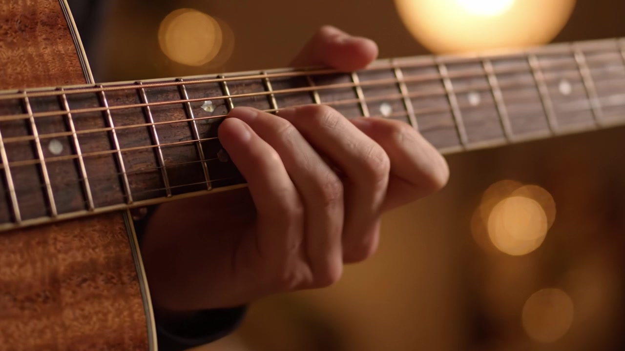 Close-Up of a Musician's Hand Skillfully Playing Acoustic Guitar Strings with Warm Bokeh Background Creating a Tranquil Atmosphere in a Cozy Setting