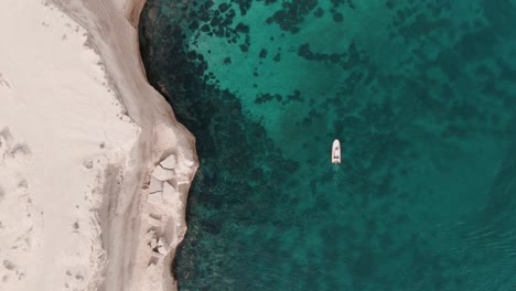 boat moving next to a cliff in patagonia from a drone top shot sixty fps