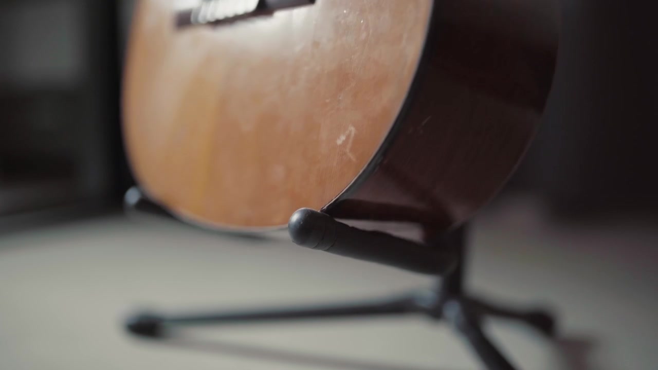 Una guitarra acústica de madera descansa sobre un soporte con una suave iluminación interior y un fondo borroso