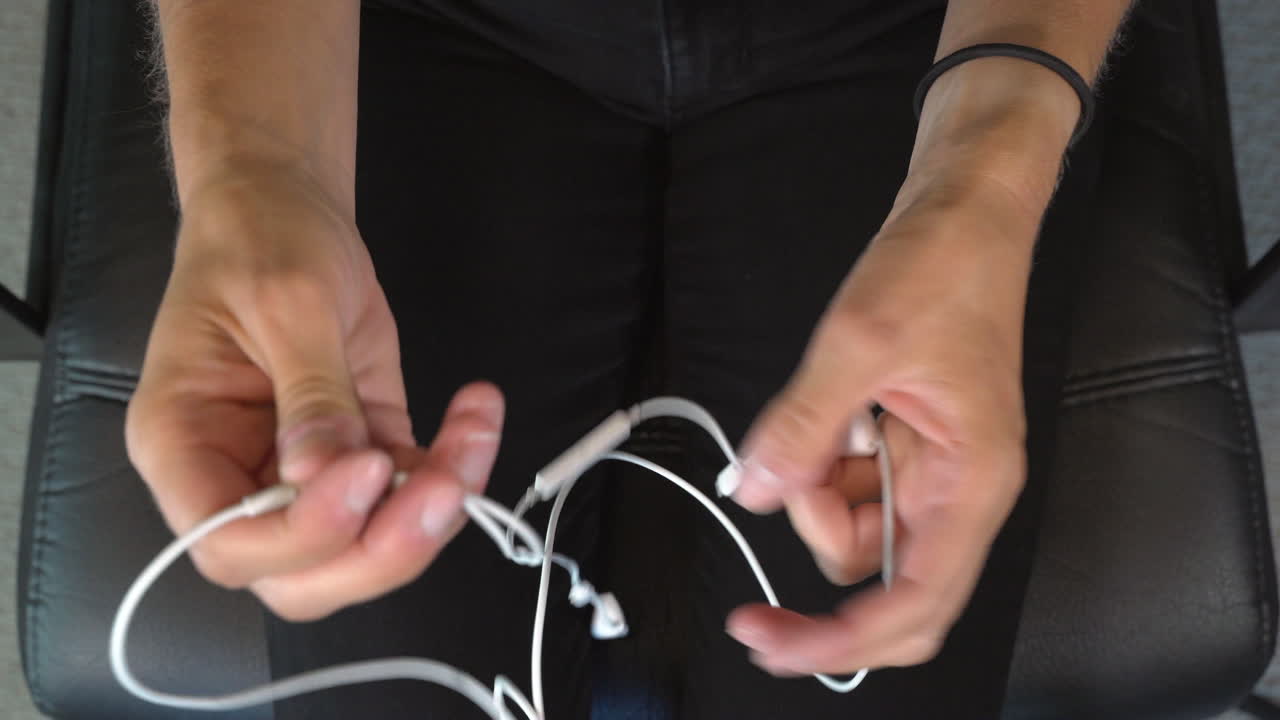 Top view of hands successfully untangling white in ear headphones