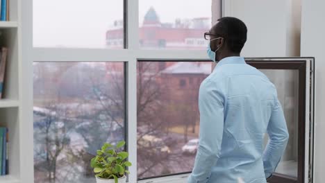 man looking out window in office