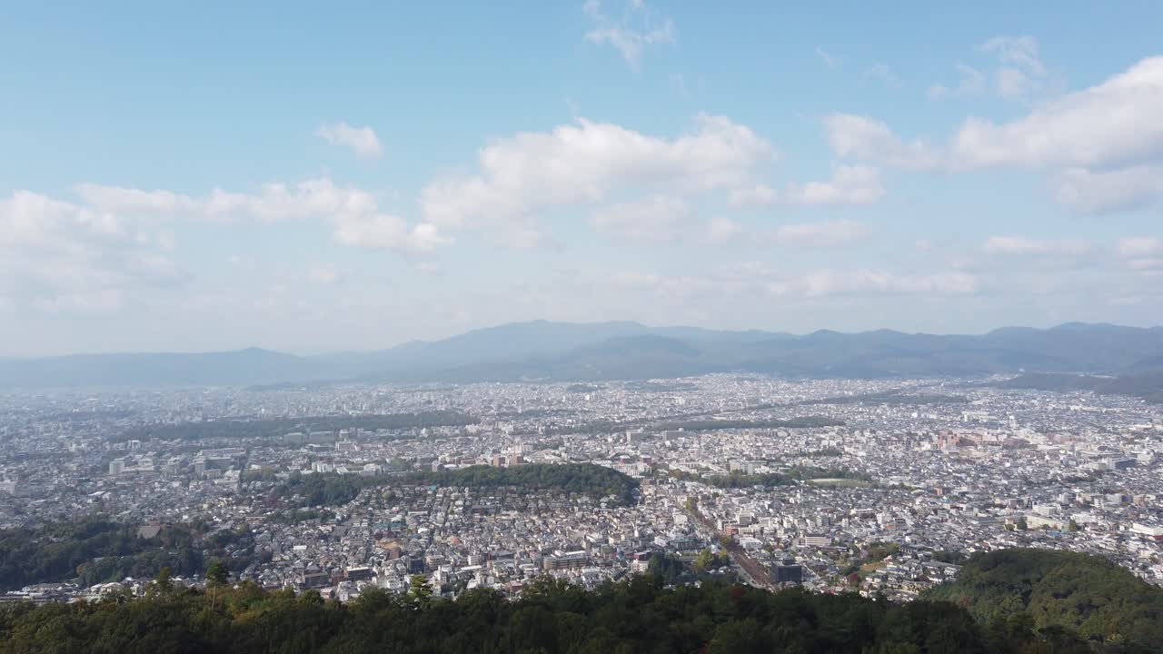 Aerial top view of Kyoto City Japan in morning daylight, urban landscape, autumn forested mountains