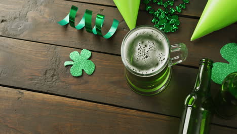 video of st patrick's green beer, shamrock and bottle on wooden background