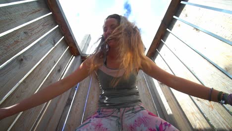 beautiful woman smiling and playing outdoors on a wooden structure on a sunny day