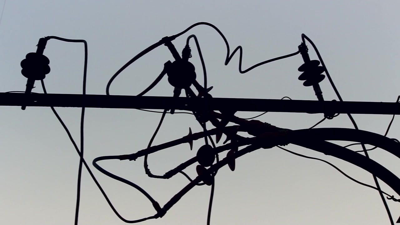 Close up silhouette of tangled electrical wires and utility pole infrastructure against clear sky, ideal for energy, electricity, urban infrastructure, power supply, and industrial themes.
