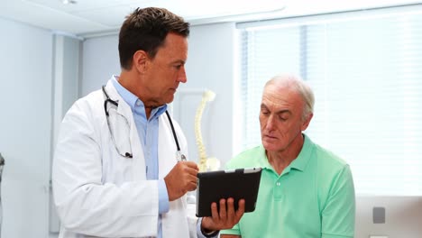 médico y paciente mayor discutiendo sobre una tableta digital