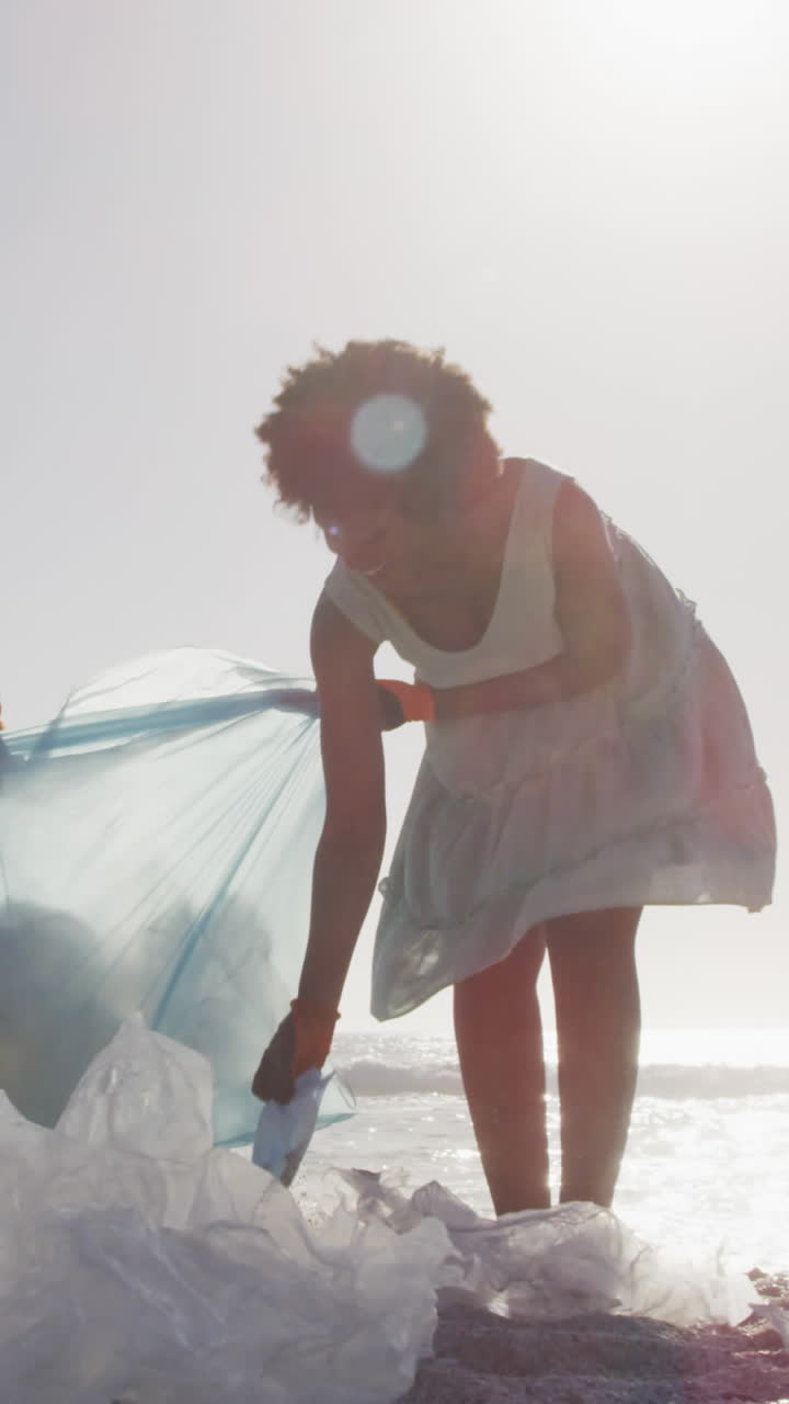 pareja afroamericana segregando residuos con guantes en una playa soleada