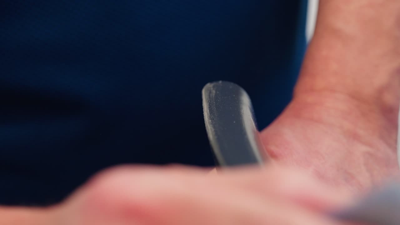 Close up shows hand sanding wooden dining chair back with sheet of sandpaper