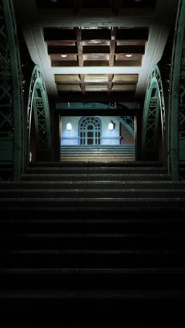 dark and mysterious staircase leading to a lit entryway under a bridge