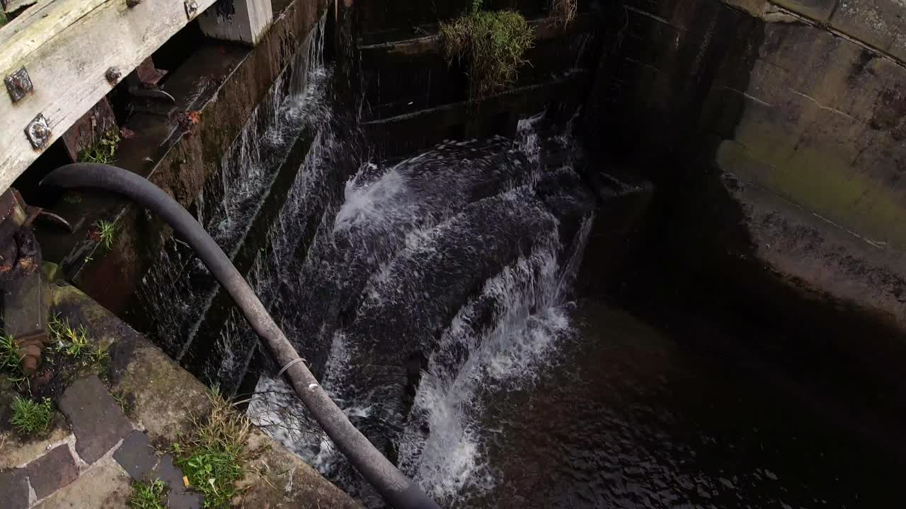 Closed waterway canal lock gates splashing pressure water cascading through wooden barrier