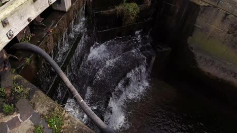 Geschlossene-Schleusentore-Des-Wasserstraßenkanals,-Die-Druckwasser-Durch-Eine-Holzbarriere-Spritzen