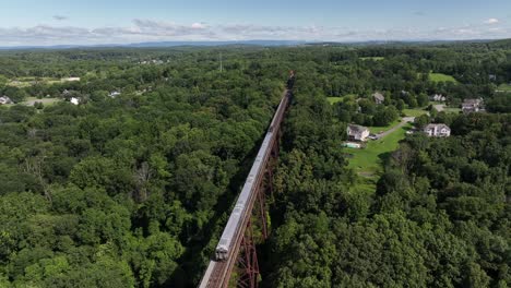 An aerial view of the Moodna Viaduct, a steel railroad trestle in Cornwall, NY with a train coming in on a sunny day
