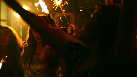 joyful crowd dancing with sparklers at party