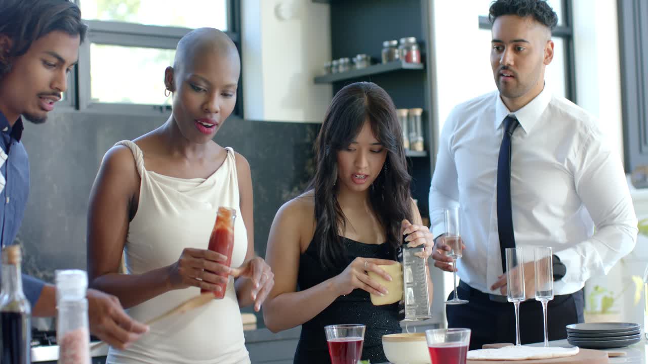 Diverse friends pointing, making pizza on board at island, grating cheese, holding flutes for party