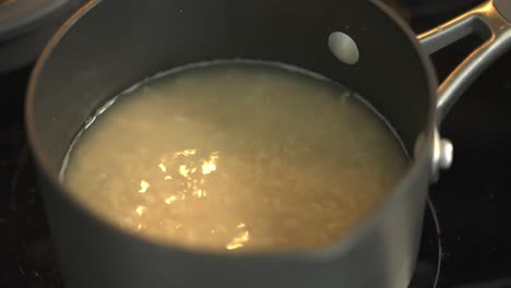 boiling water on n electric stove to cook raw whole grain rice in a medium saucepan