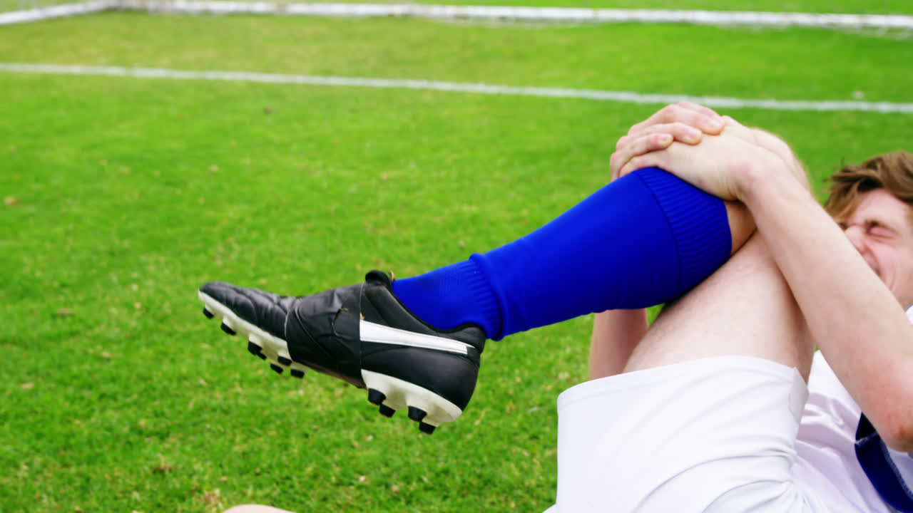Jogador de futebol lesionado deitado na grama