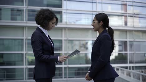 cheerful colleagues exchanging documents on street.