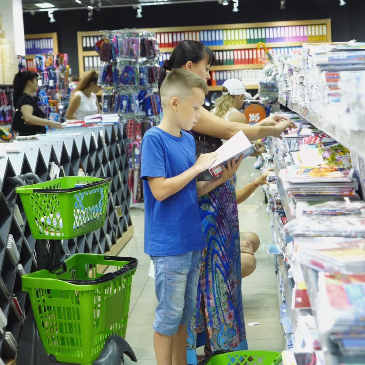 VINNITSA, UKRAINE - AUGUST 20, 2018: Back to school concept. Young mother and little boy buying school supplies in store.