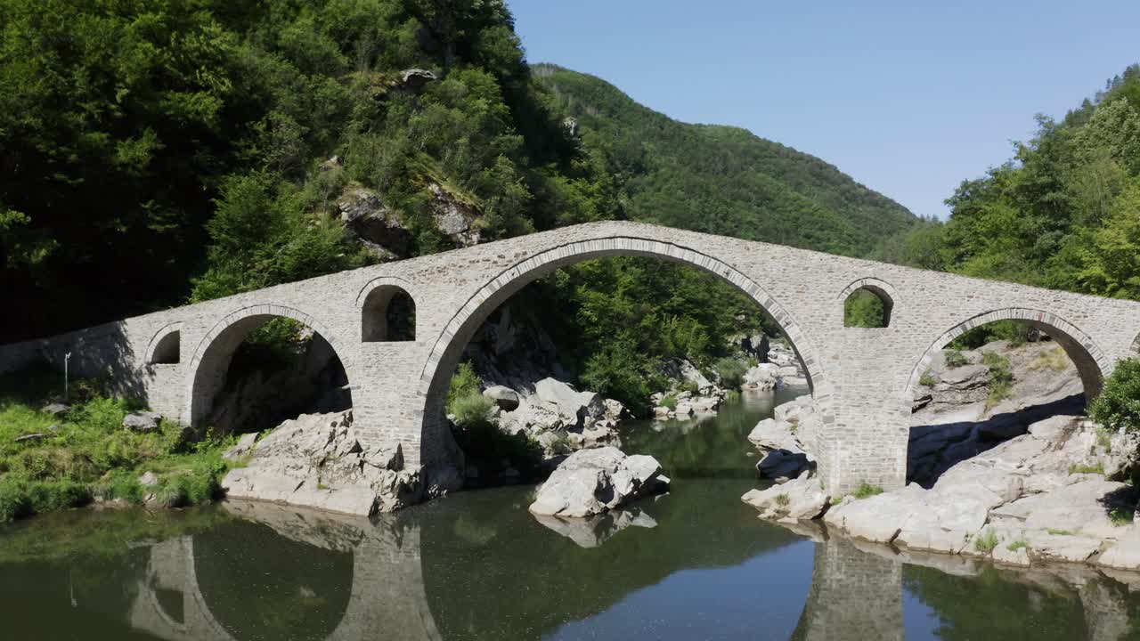 Retreating drone shot showing the length of the Devil's Bridge and the Arda River situated in the town of Ardino near the Rhodope Mountains in Bulgaria
