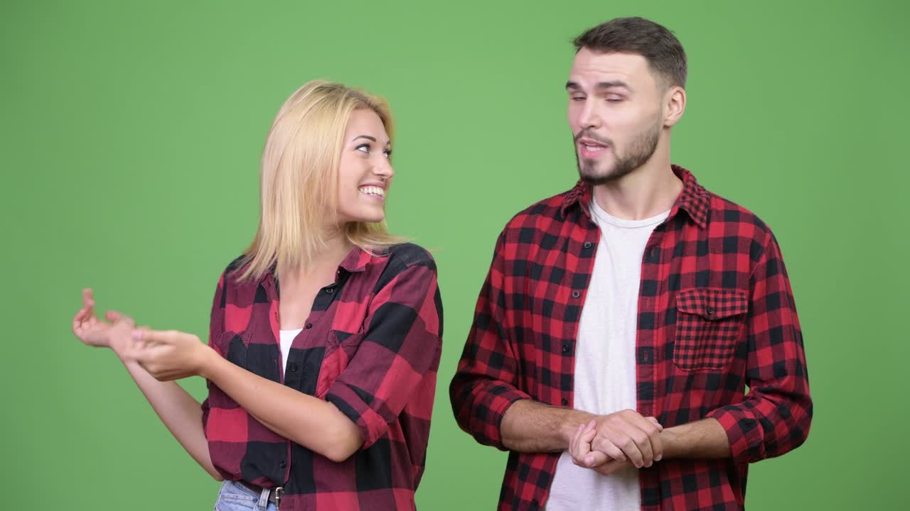 Young couple showing something and talking to camera together
