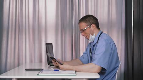 upset-doctor-does-video-call-with-tablet-at-table-in-office