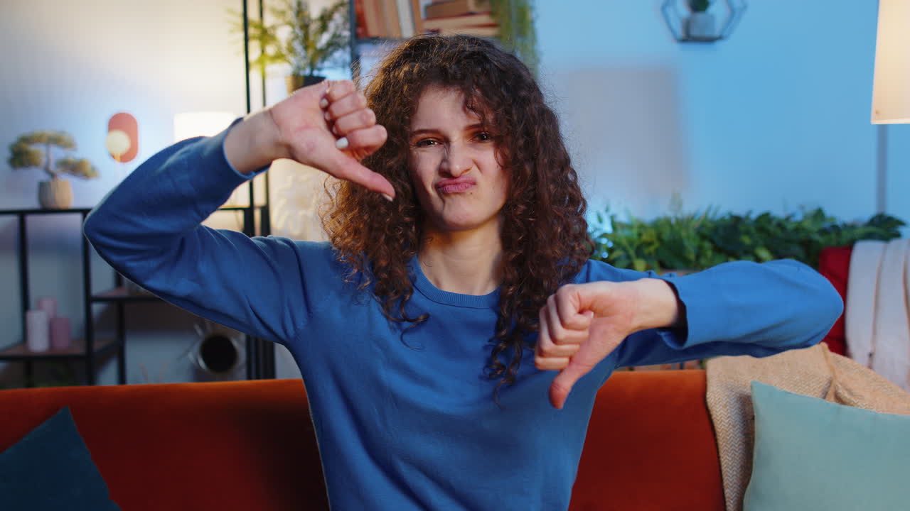 Displeased upset young woman showing thumbs down dislike gesture expressing discontent disapproval