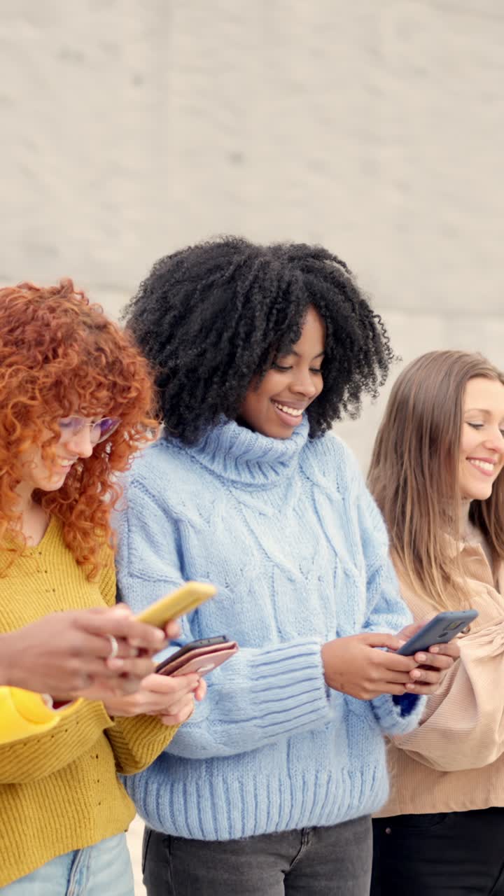 Women looking at cellphone smiling on the street
