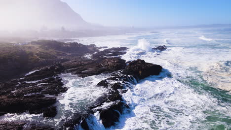 aerial riser over rocky coastline as waves keep rolling in