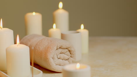 still life of lit candles with incense stick and soft towels as part of relaxing spa day decor