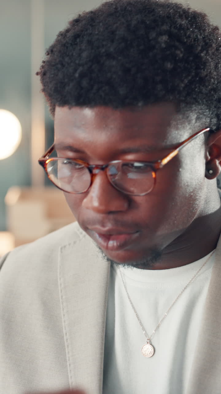Young Black Man Puts On Glasses and Looks Down